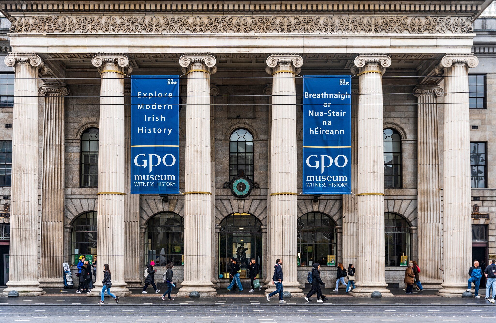 Neoclassical facade of General Post Office, headquarters of leaders of Easter Rising, in O'Connell Street, Dublin city center, Ireland. Pedestrians walking past.