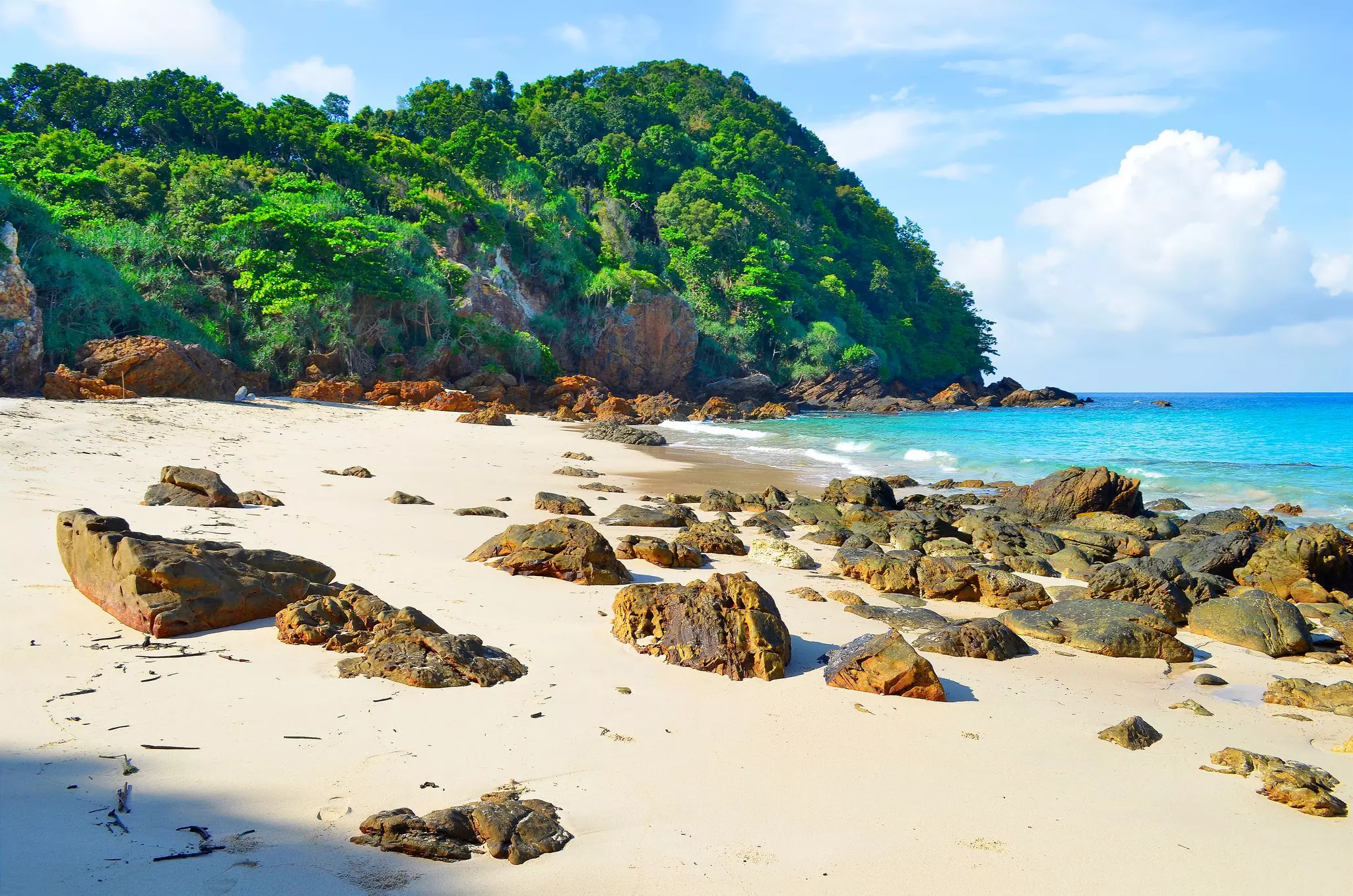 A beach with large boulders dotting the golden sand