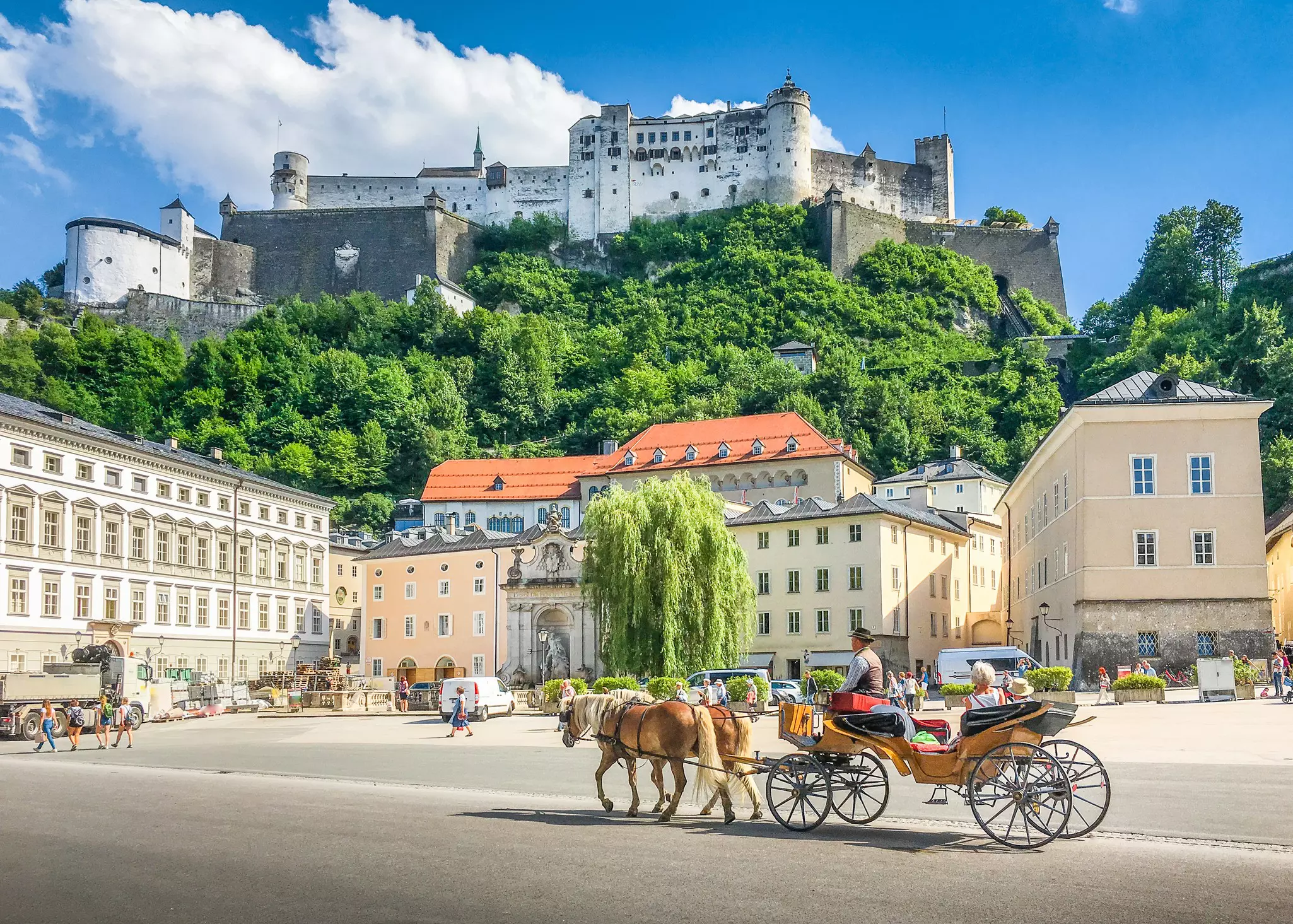 Beautiful panoramic view of the historic city of Salzburg with traditional horse-drawn fiaker carriage and  Hohensalzburg Fortress in summer