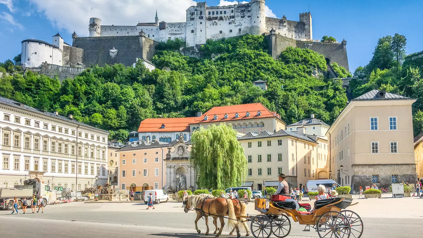 Beautiful panoramic view of the historic city of Salzburg with traditional horse-drawn fiaker carriage and  Hohensalzburg Fortress in summer