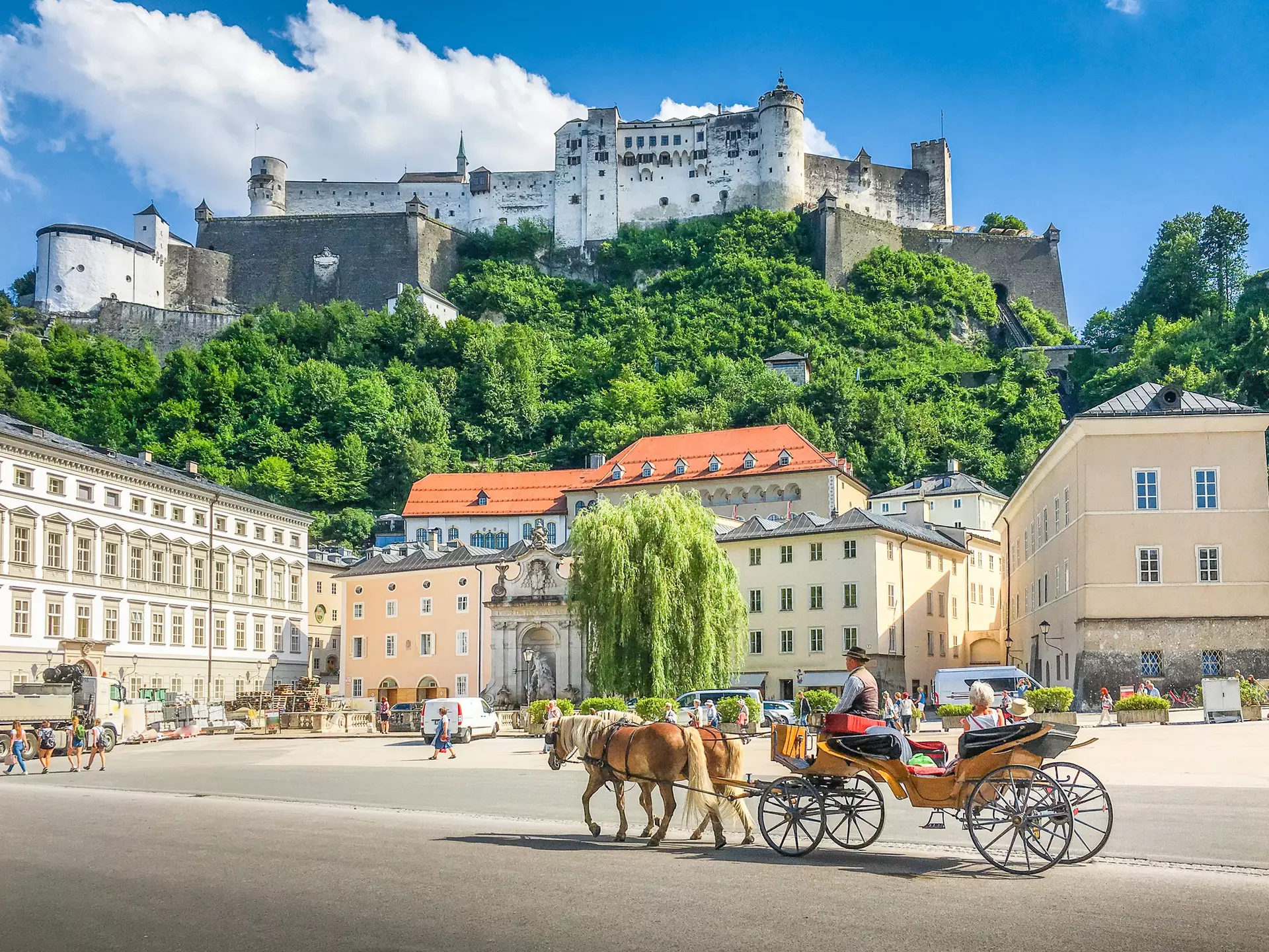 Beautiful panoramic view of the historic city of Salzburg with traditional horse-drawn fiaker carriage and  Hohensalzburg Fortress in summer