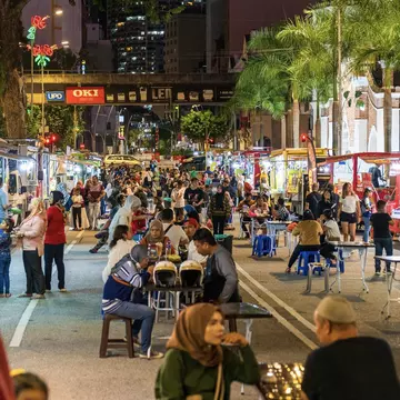 People sitting at tables in a street market