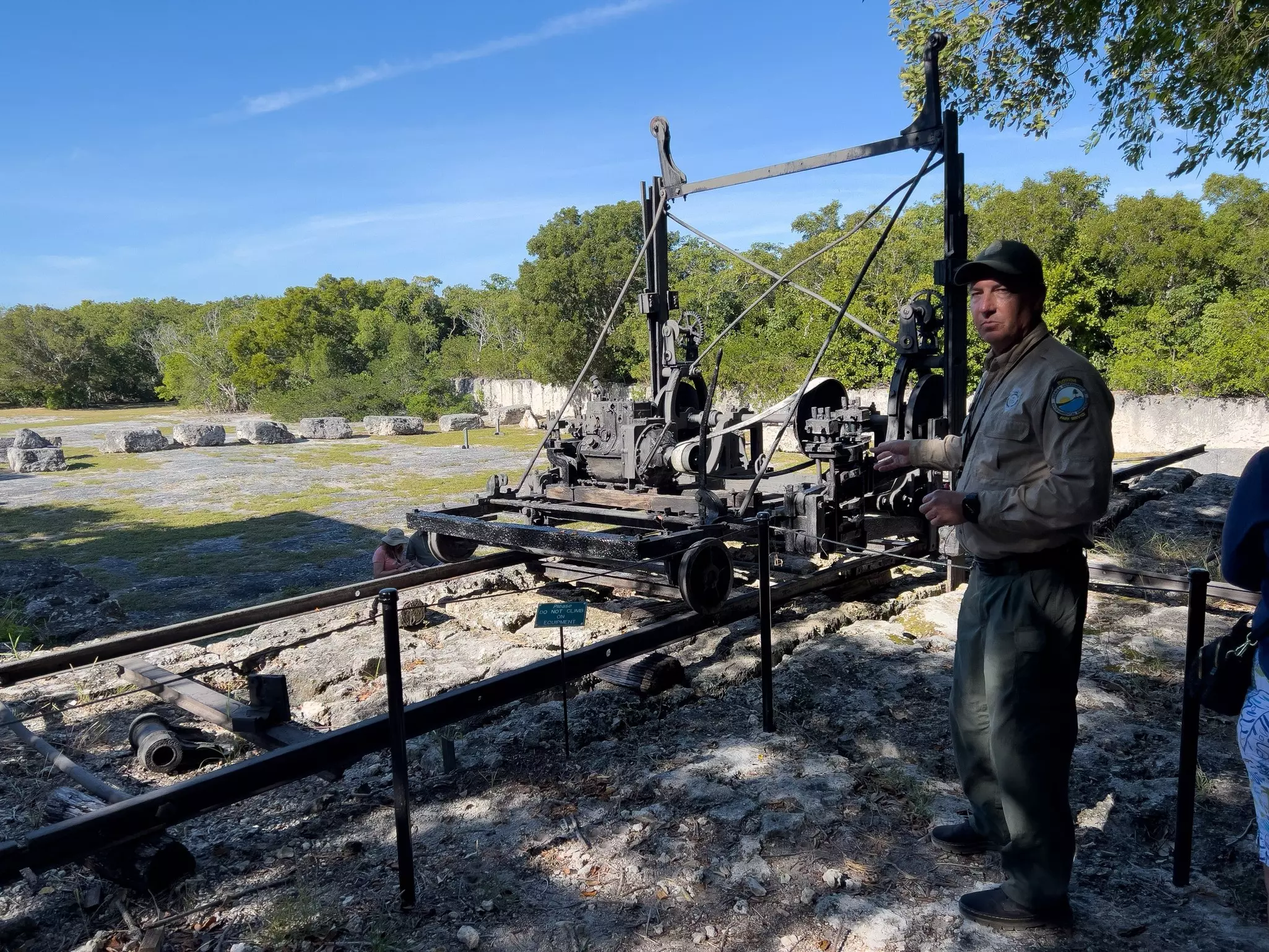 A park ranger stands beside rusting equipment in a former quarry at a state park in the Florida Keys.