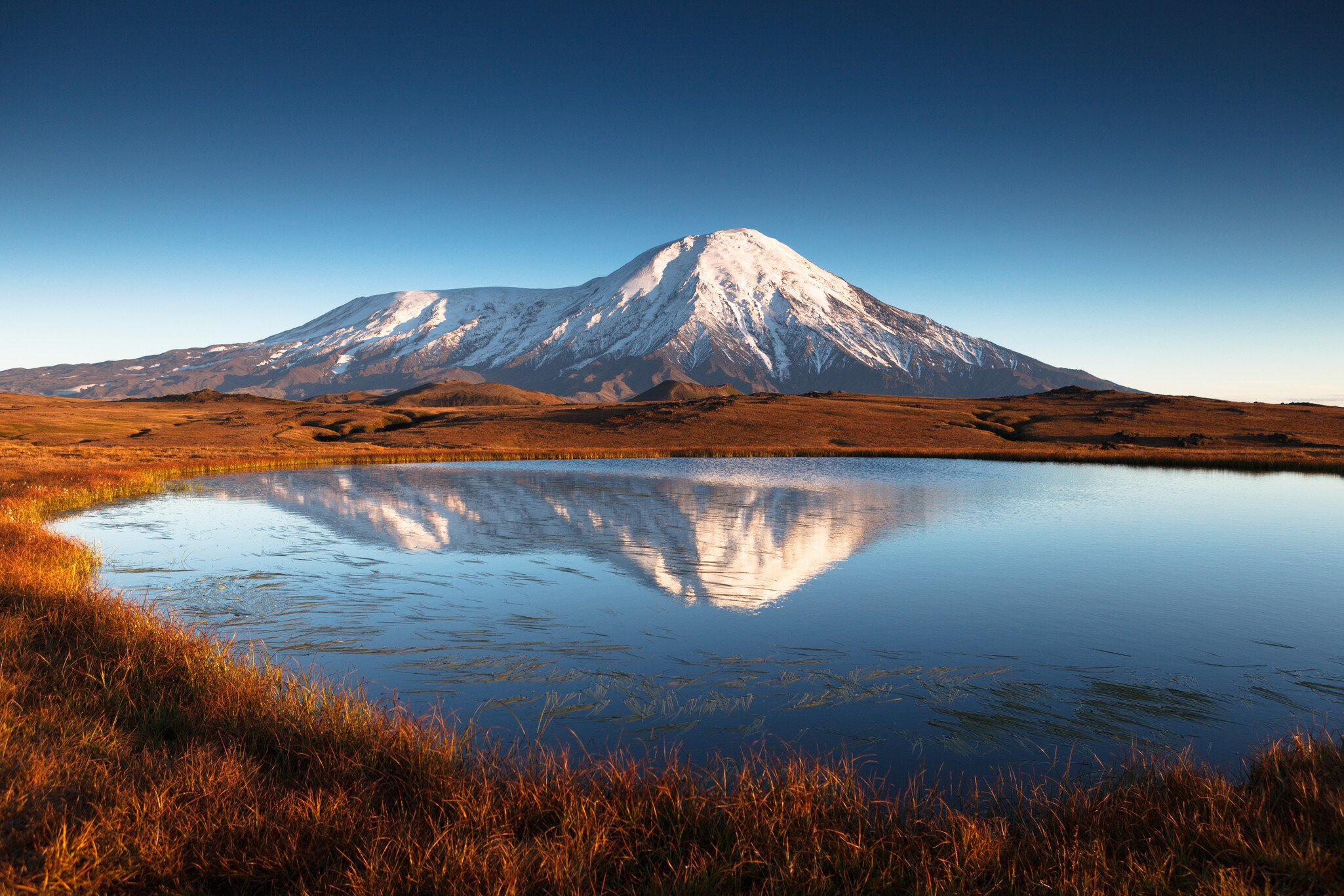 Snowcapped mountain with lake in foreground, Kamchatka, Russia