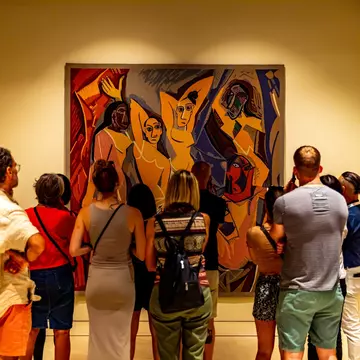 Museum visitors looking at a large Picasso painting of four people