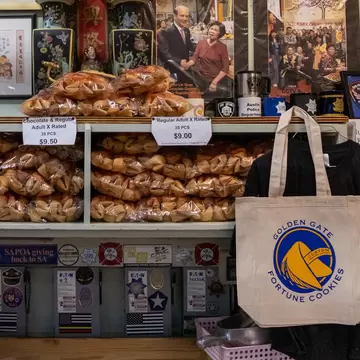 Founded in 1962, the Golden Gate Fortune Cookie Factory has been dedicated to producing handmade, high quality and customizable fortune cookies. Located in Ross Alley in the heart of San Francisco's Chinatown, visitors from all over the world are invited inside our shop to experience the cookie making process in person.,,Up to 10,000 fortune cookies are made a day, depending on the season! Cookies are baked fresh on a copper slow-release heat rotating griddle wheel. They are then gently twisted into the famous fortune cookie shape as the message is carefully placed inside. In addition to the traditional vanilla flavored cookies, they make chocolate, strawberry, green tea and glazed cookies.
