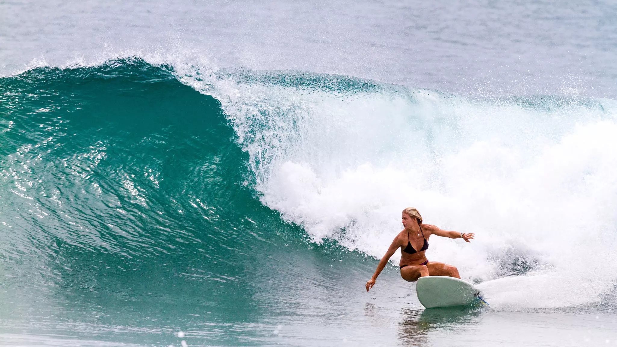 A woman surfing ocean waves in the South China Sea in Hainan, China.