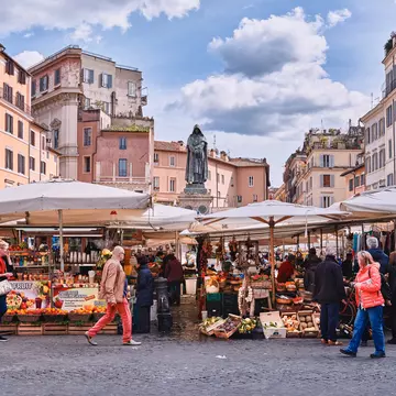 March 8, 2018: Traditional outdoor food market of Campo de Fiori (fields of flower), with the statue of Giordano Bruno in the background.