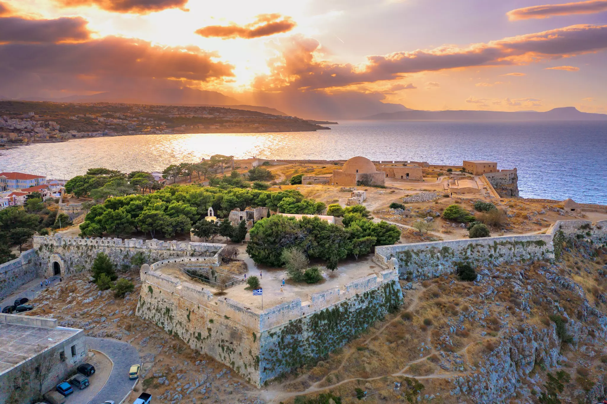 A large coastal fortress with ancient stone walls at sunset.