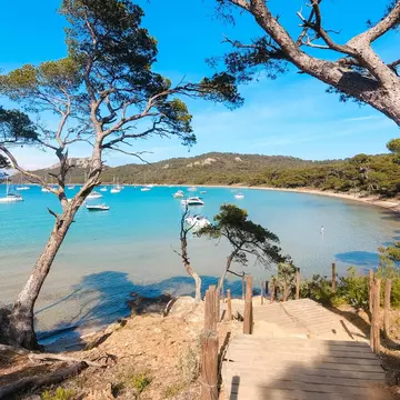 A wood pathway leads to a deep blue cove with boats.
