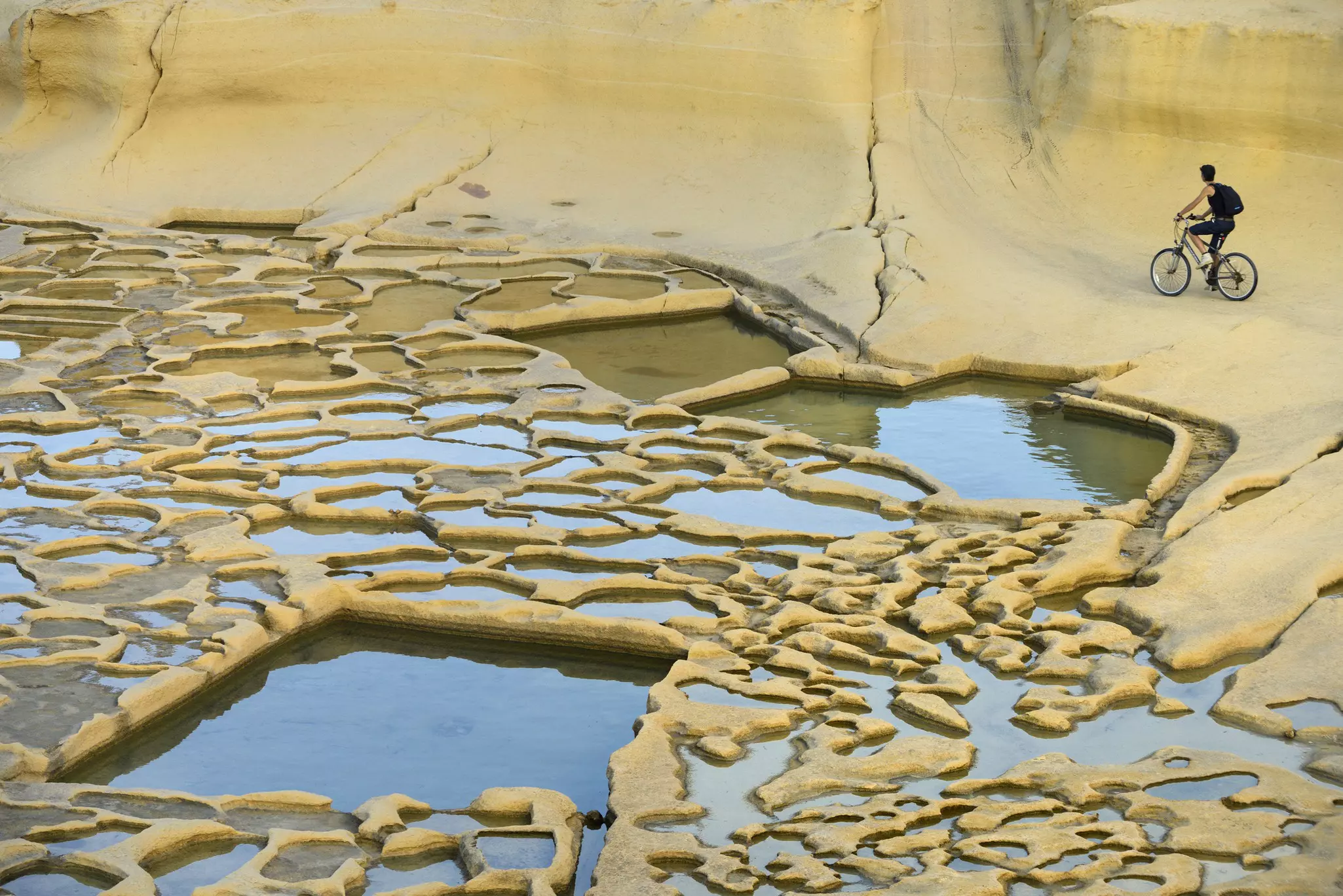 A cyclist pauses at Gozo's ancient salt pans.