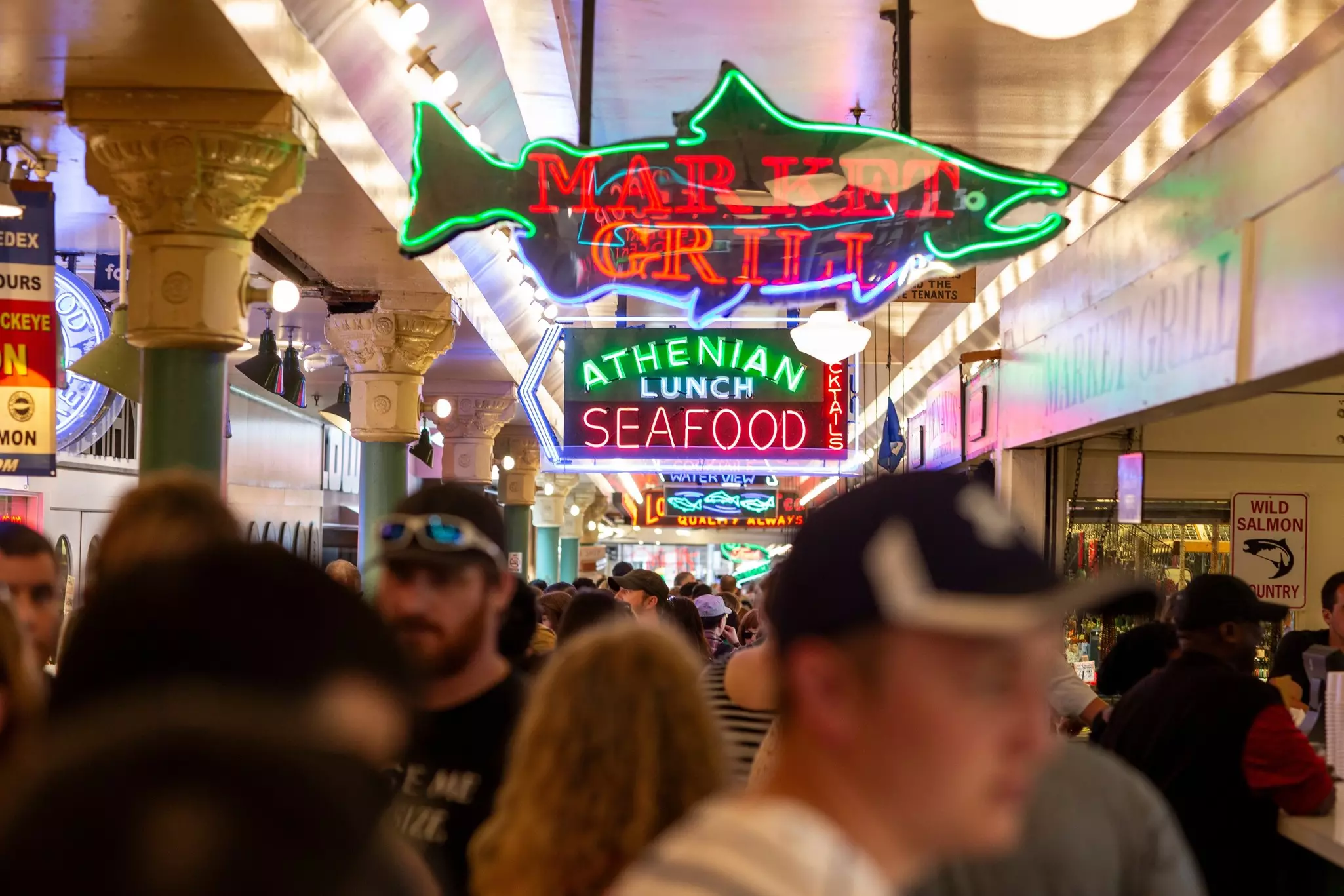 Crowded indoor market with neon signs advertising seafood