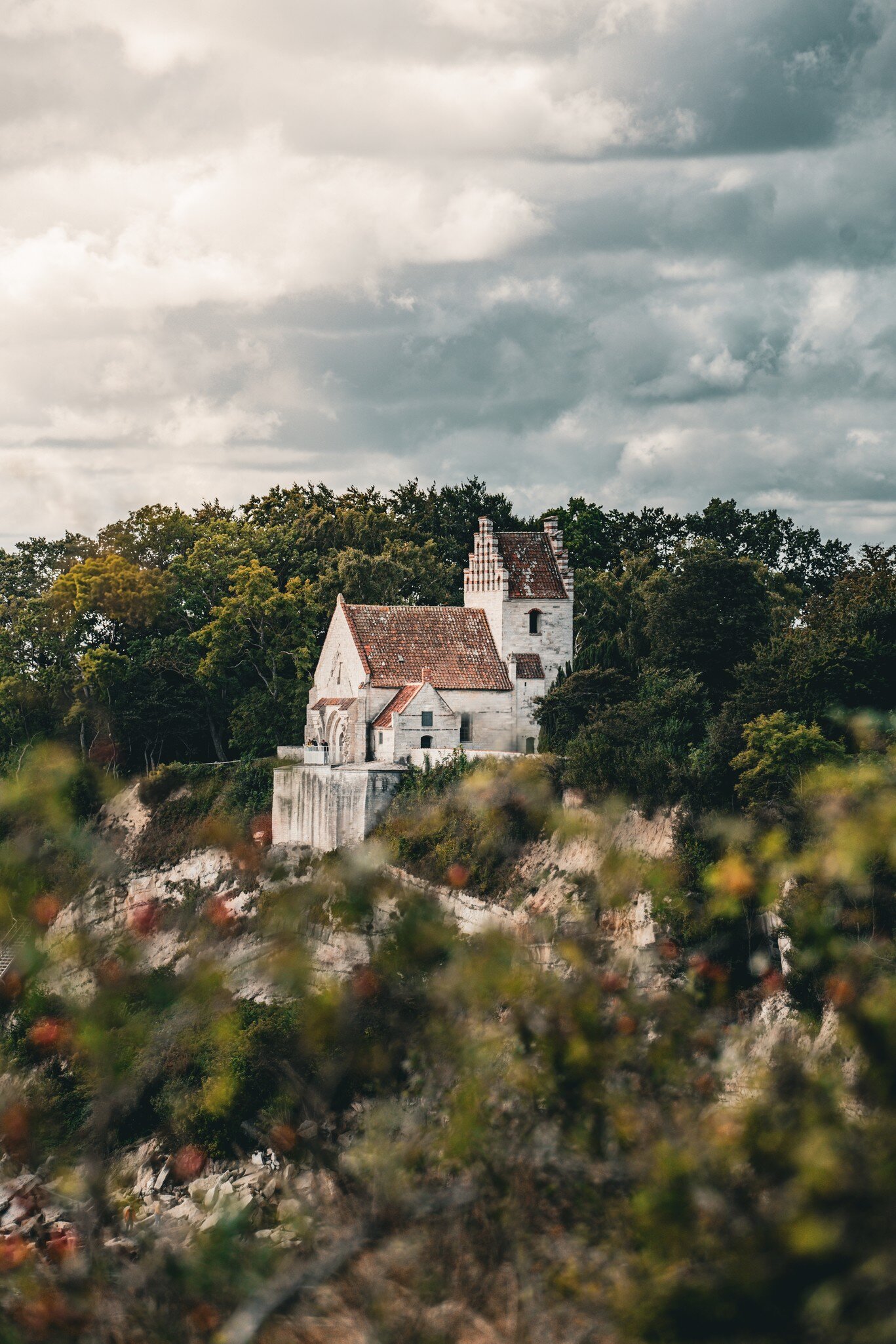 Højerup Gamle Kirke in Stevns, Denmark. Surrounded by trees and cliffs.