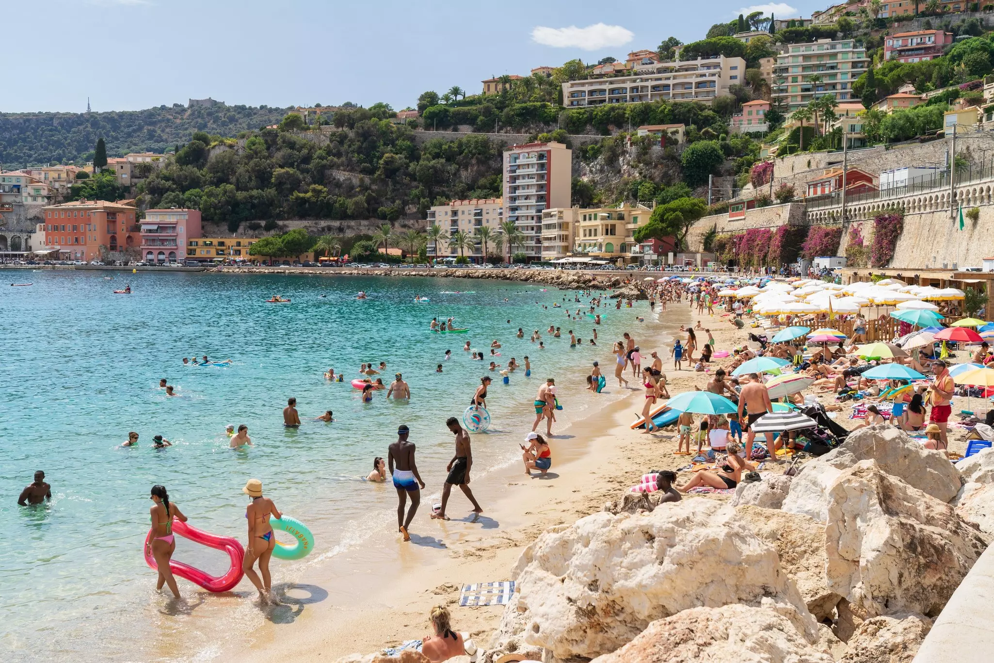 A very busy beach with people swimming and sunbathing
