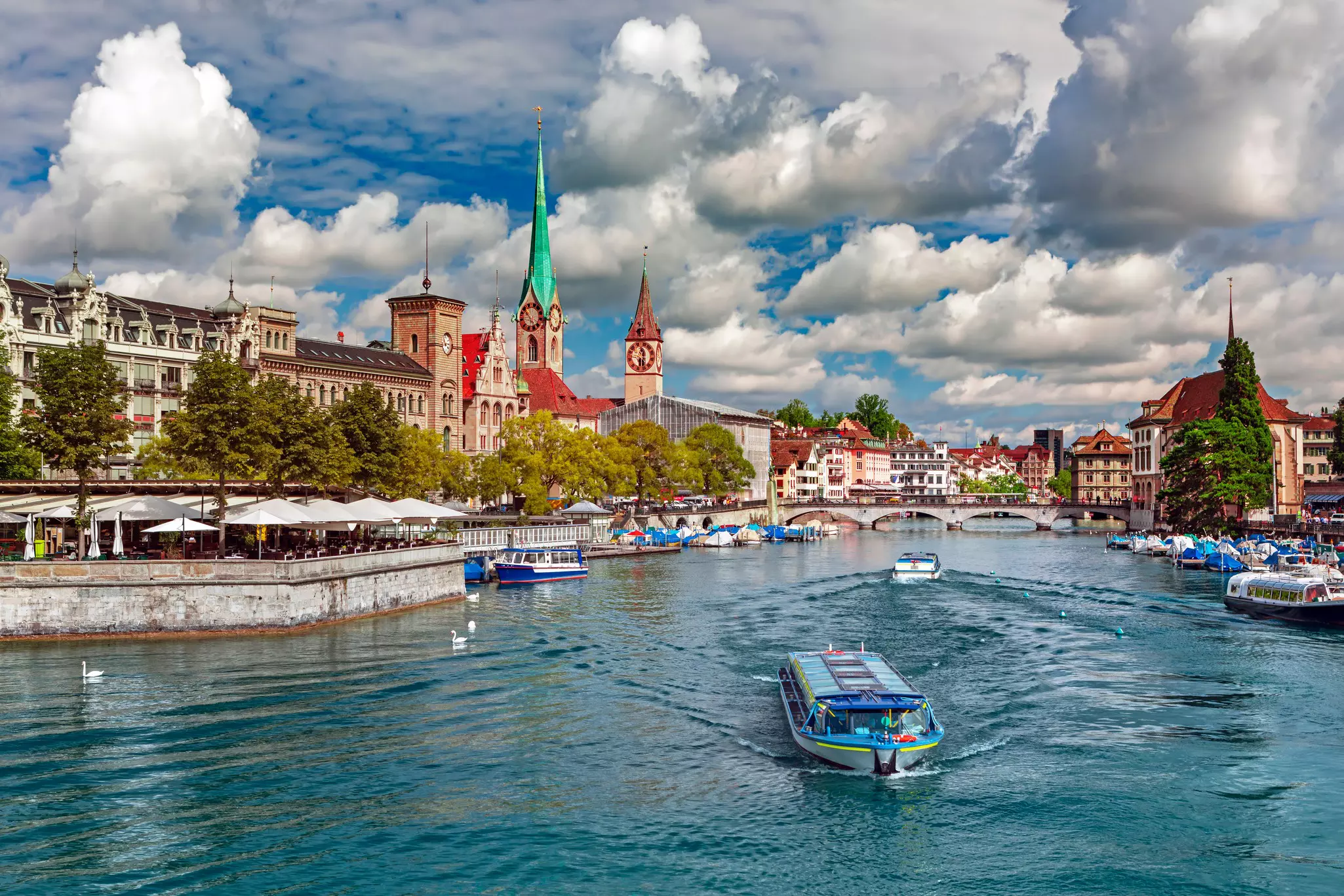 A boat travels on a blue river through a historic city in Switzerland.