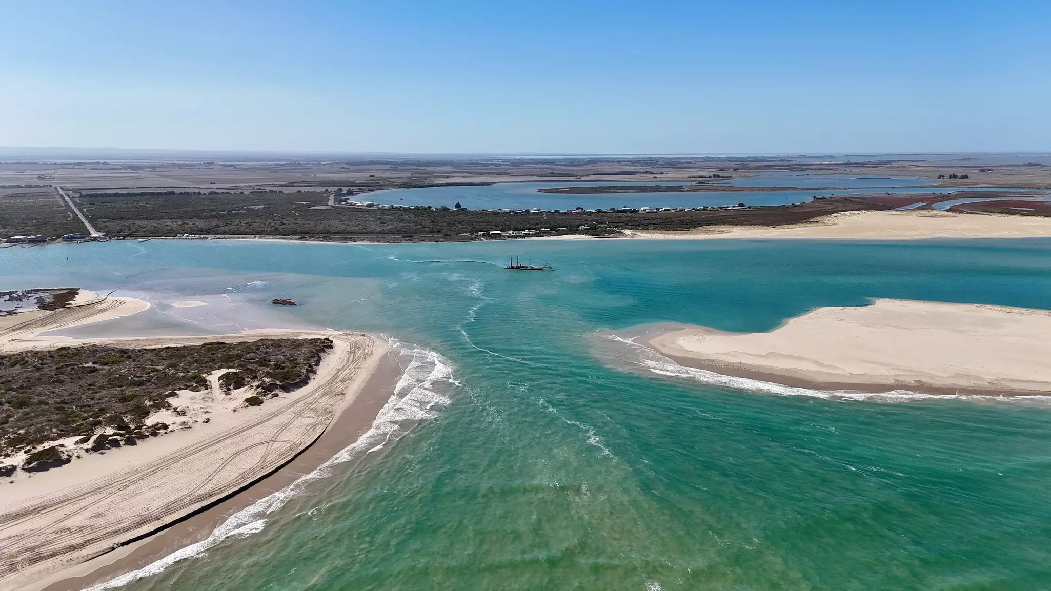 A river mouth flowing into the ocean surrounding by sandy beaches.