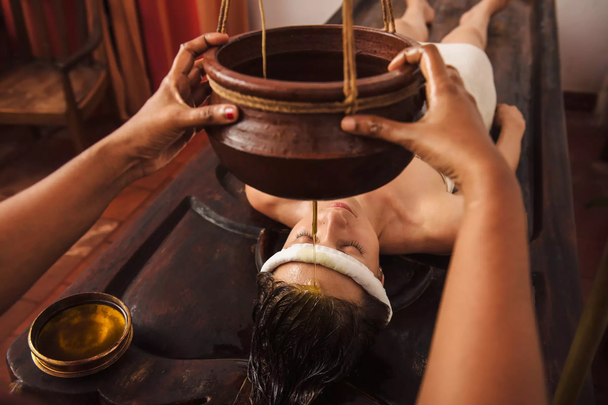 A woman enjoying a shirodhara treatment at an Ayurvedic center in India.