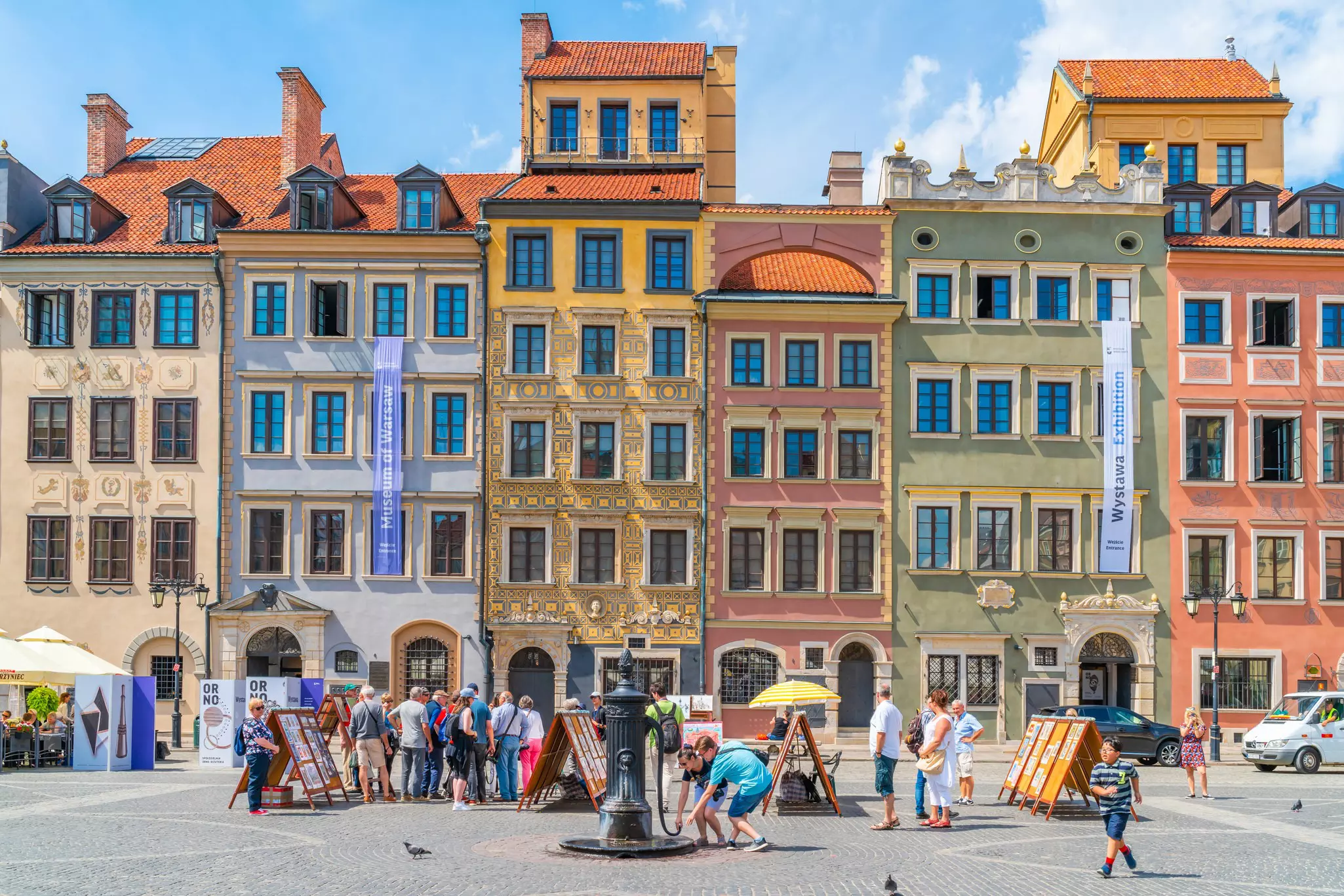 Crowds of people enjoy a sunny day in front of the colourful buildings of Warsaw.