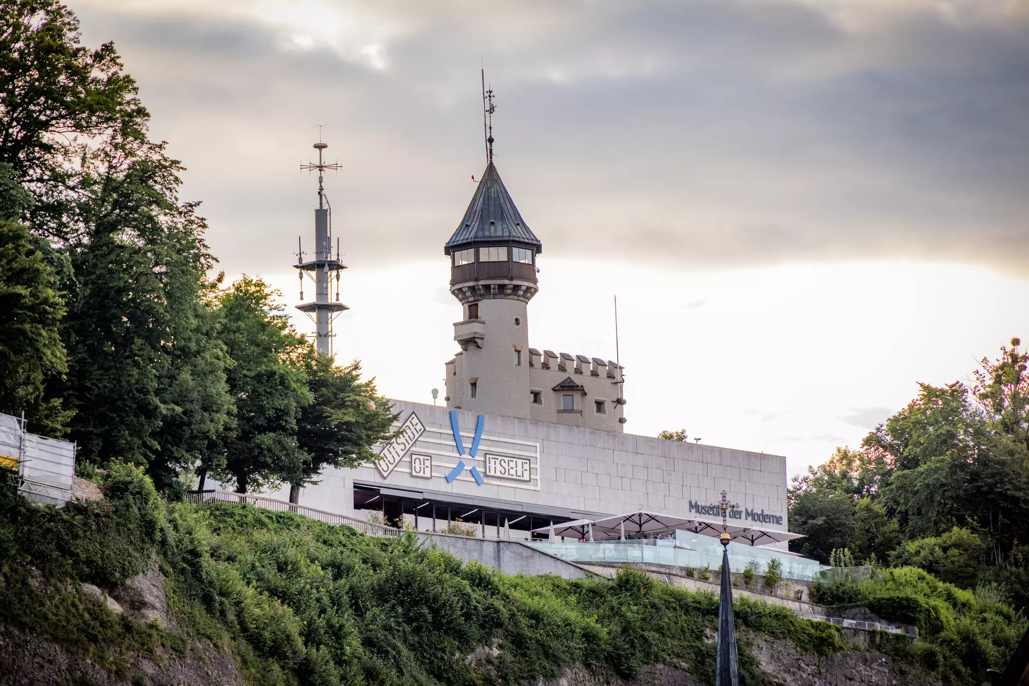 A museum building that combines an old tower and a modern style, perched on a cliff