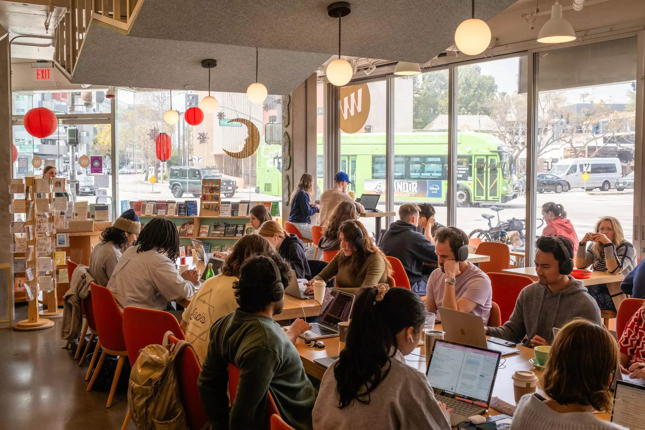 Lines of tables and people with laptops in a bright cafe