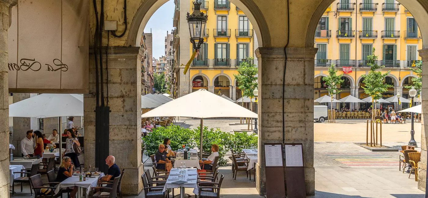 People seated at an outdoor restaurant in a square.
