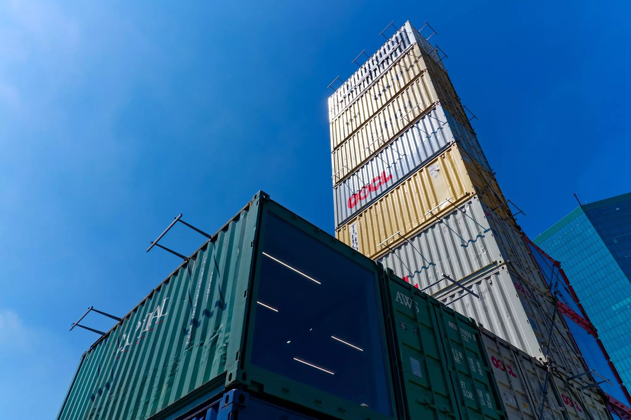 A tower made of shipping containers is pictured against a blue sky.