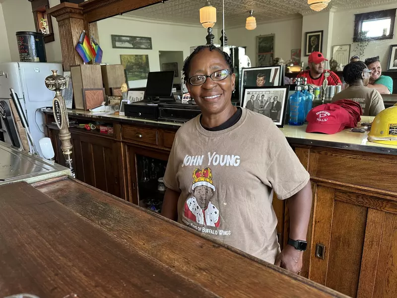 Lina smiling. She's in a brown shirt with a sketch of her dad John Young dressed as a king. 