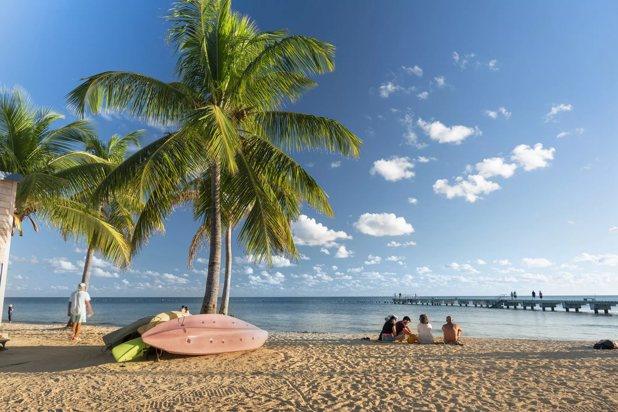 People sitting on the sand under palm trees at Smathers Beach in Key West Florida
