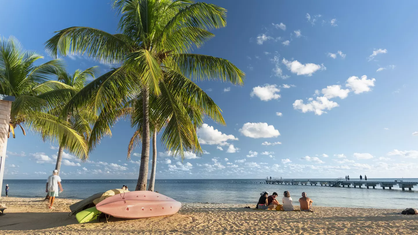 People sitting on the sand under palm trees at Smathers Beach in Key West Florida