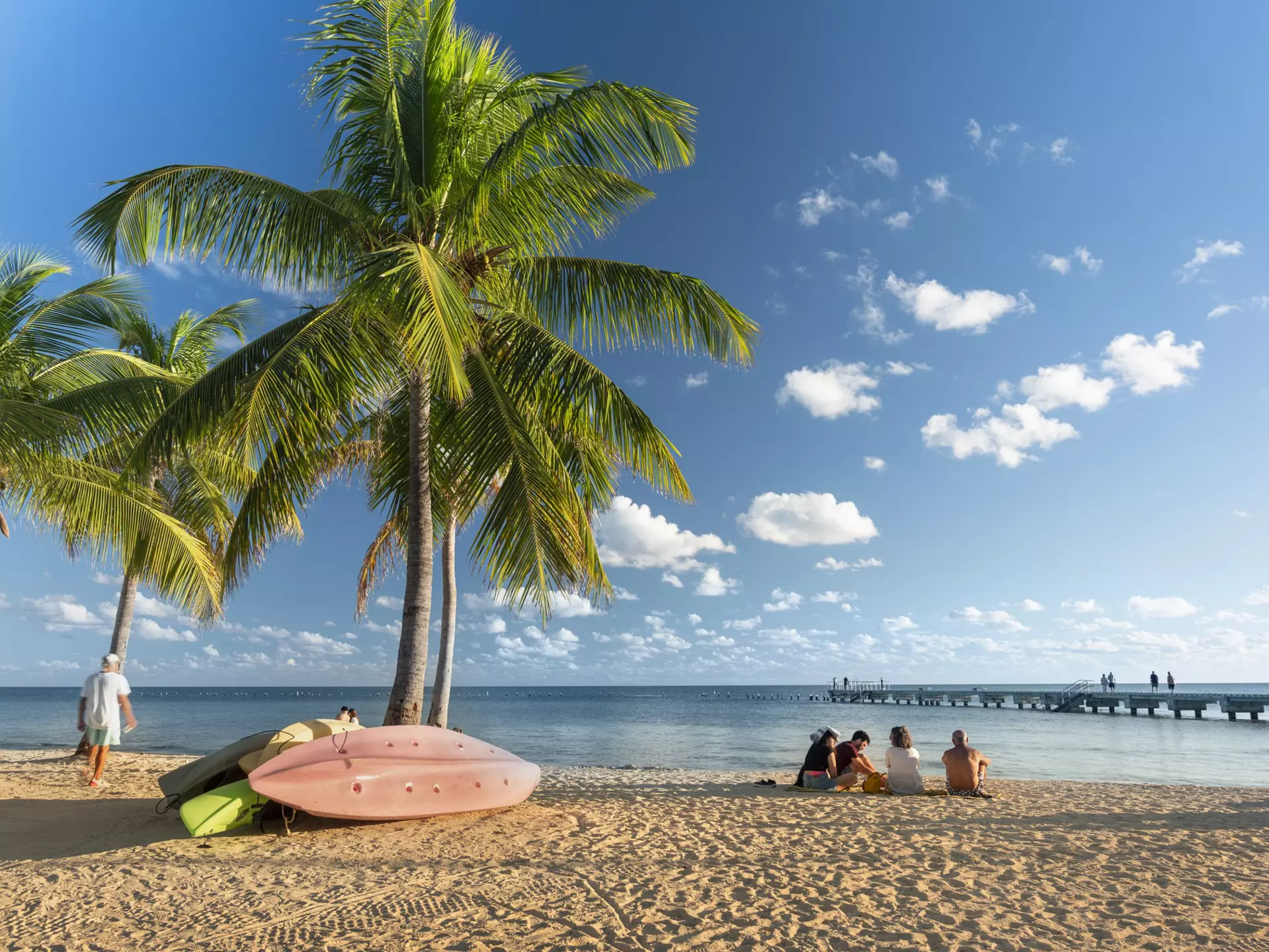 People sitting on the sand under palm trees at Smathers Beach in Key West Florida