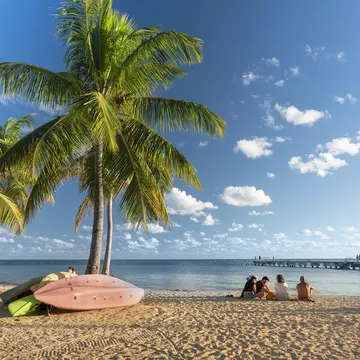 People sitting on the sand under palm trees at Smathers Beach in Key West Florida