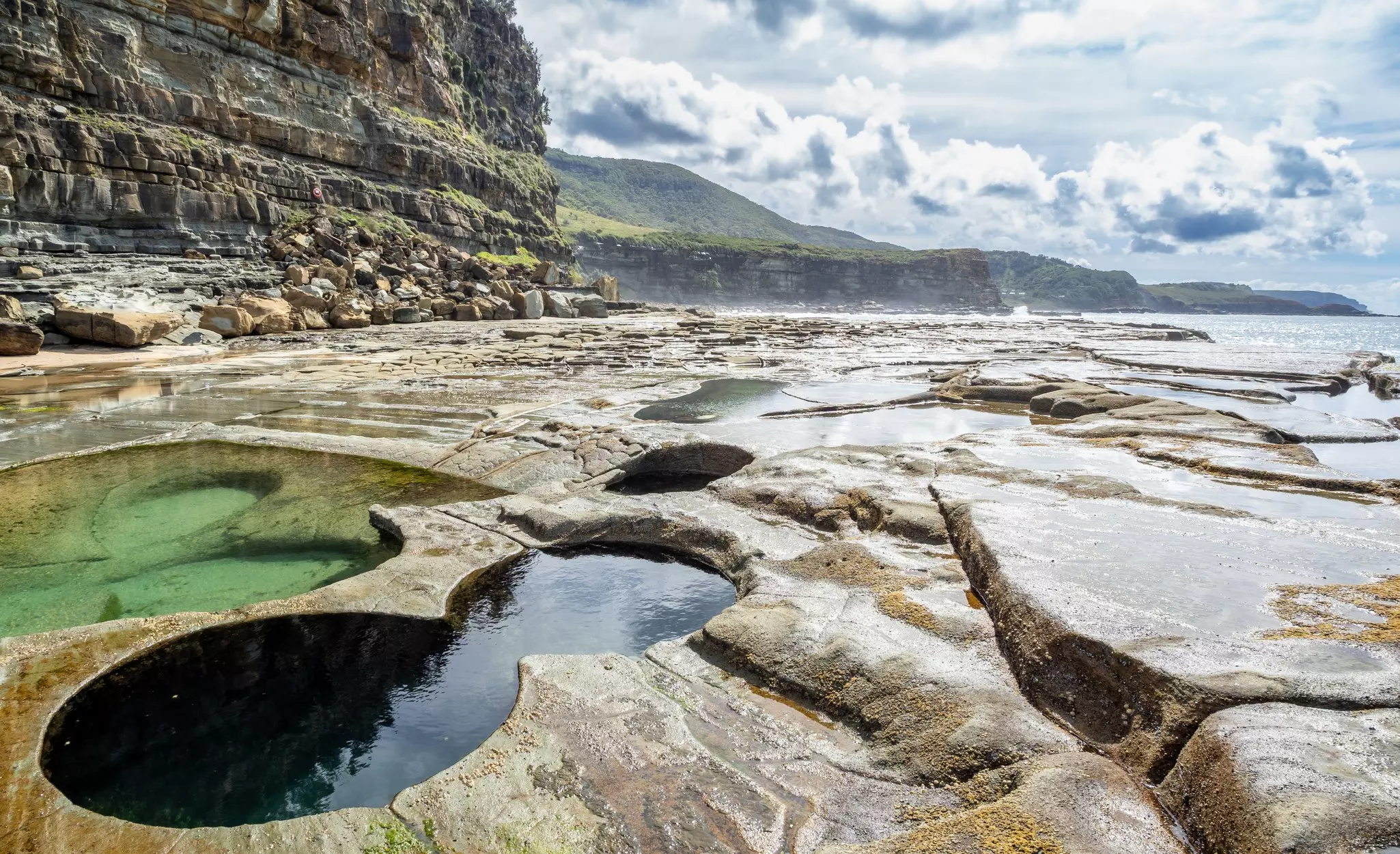 A shoreline at low tide with distinct pools of water shaped like a figure of eight.