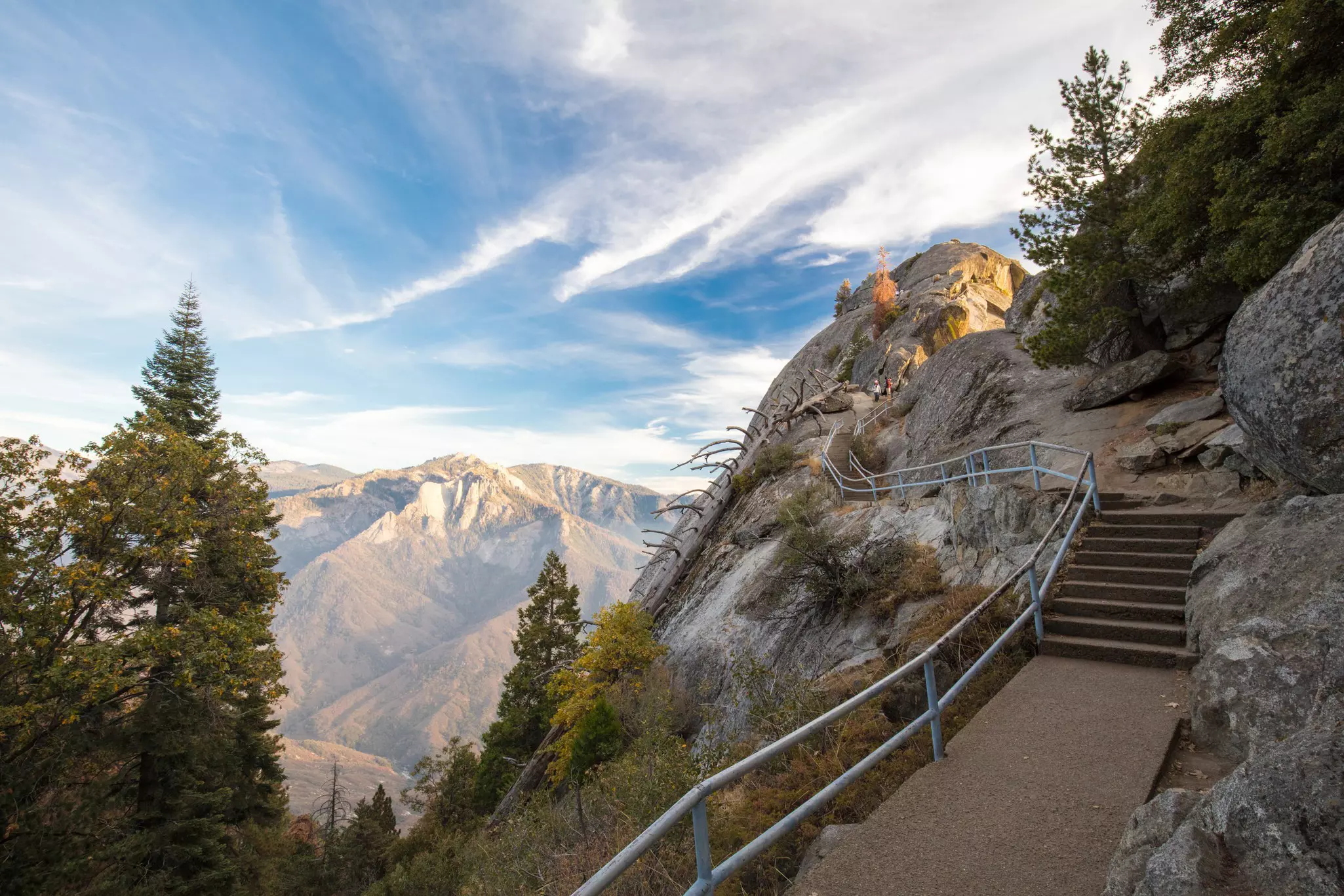 Stairs lead to a rock that overlooks a mountain range.