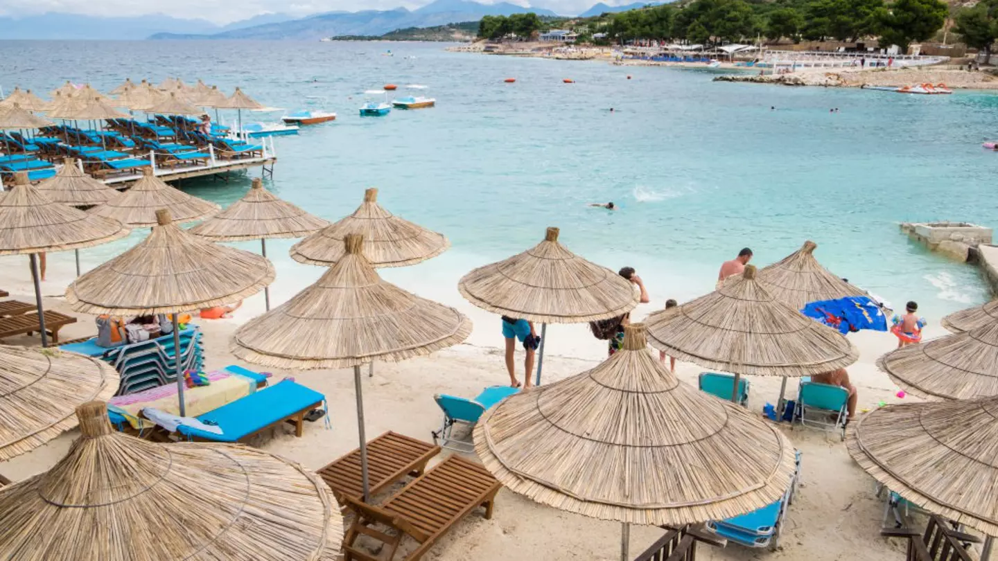 Sun umbrellas on the beach at Ksamil, Albania, with a blue bay behind.