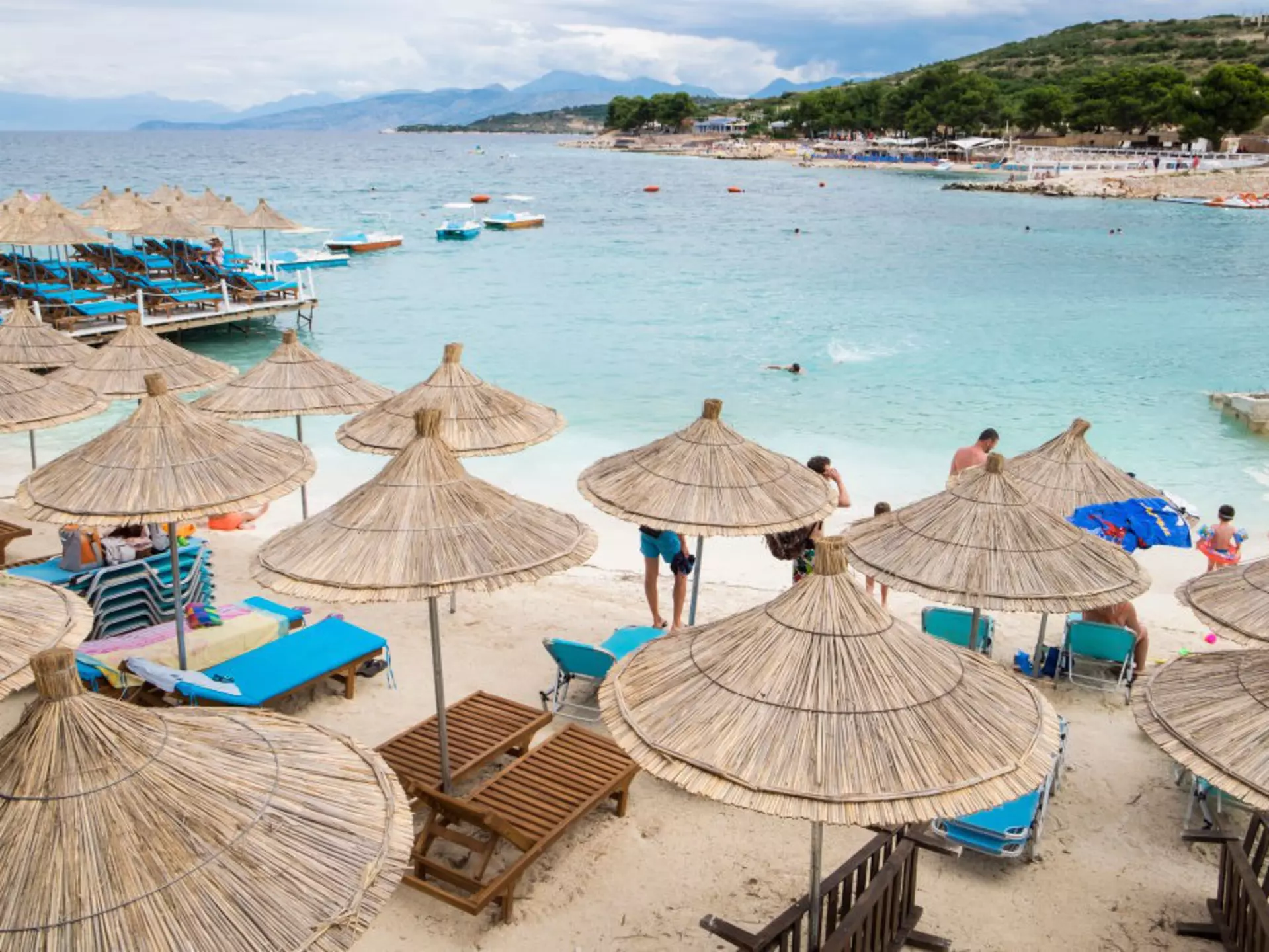 Sun umbrellas on the beach at Ksamil, Albania, with a blue bay behind.