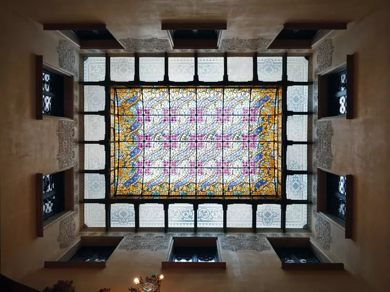 A stained glass ceiling with a colorful central design surrounded by smaller panels on the perimeter.