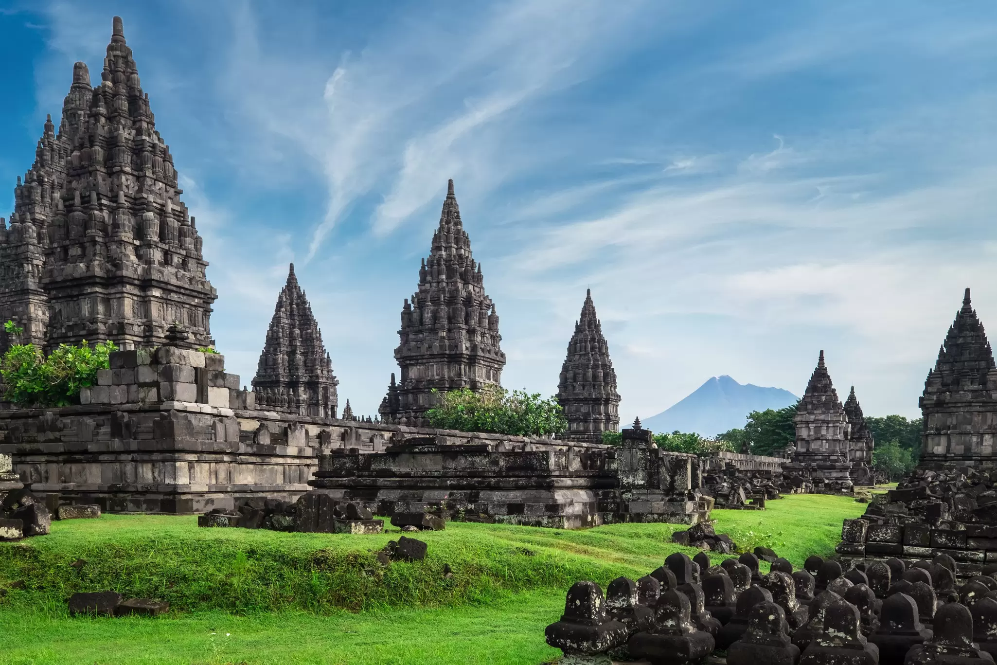 View of ancient stone ruins on a green field at Prambanan Temple in Java, Indonesia.