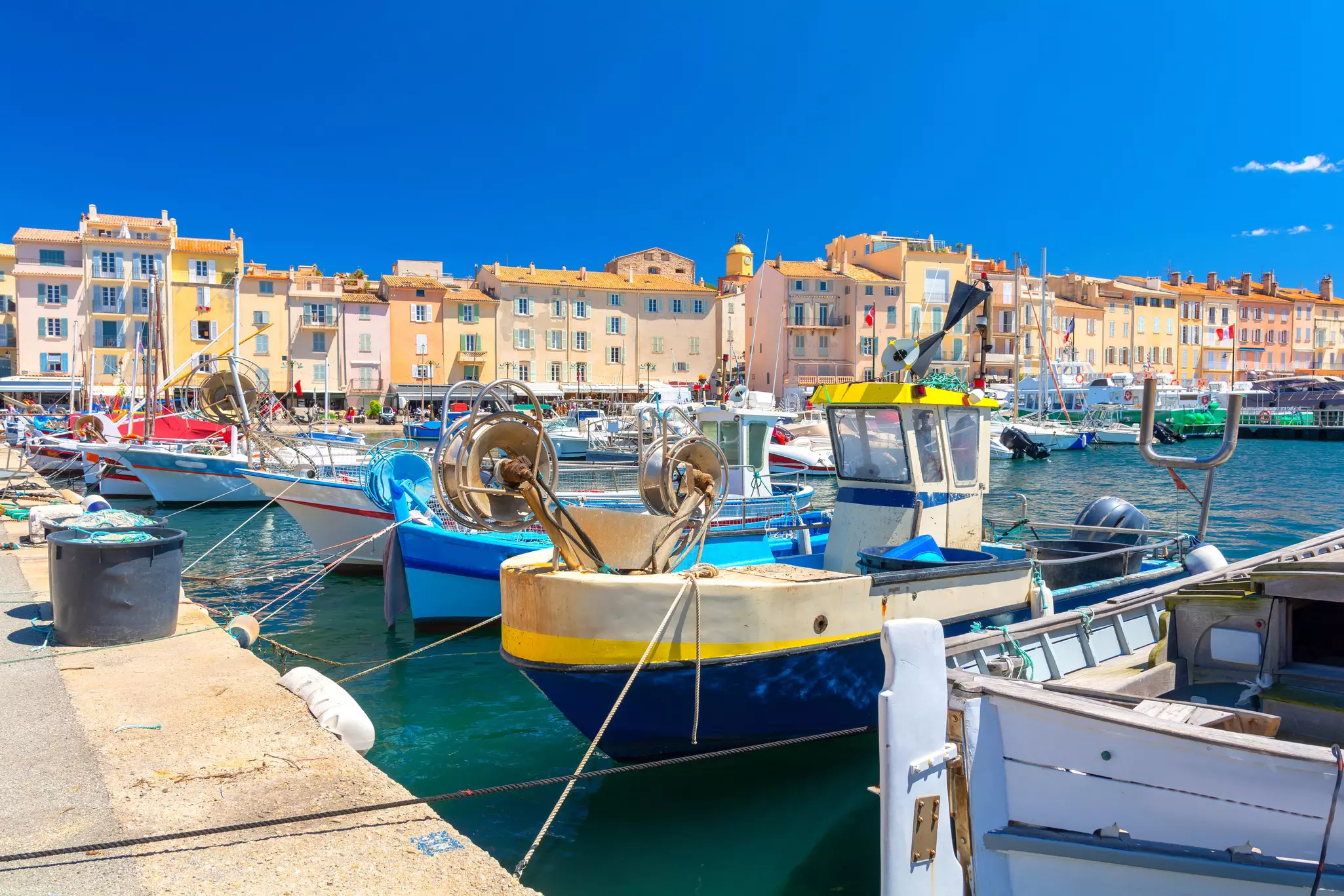 Small boats docked in a harbor backed by pastel-colored buildings