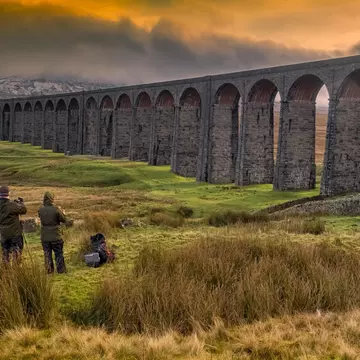 Photographers capturing the Ribblehead Viaduct on the Settle-Carlisle railway in low light.