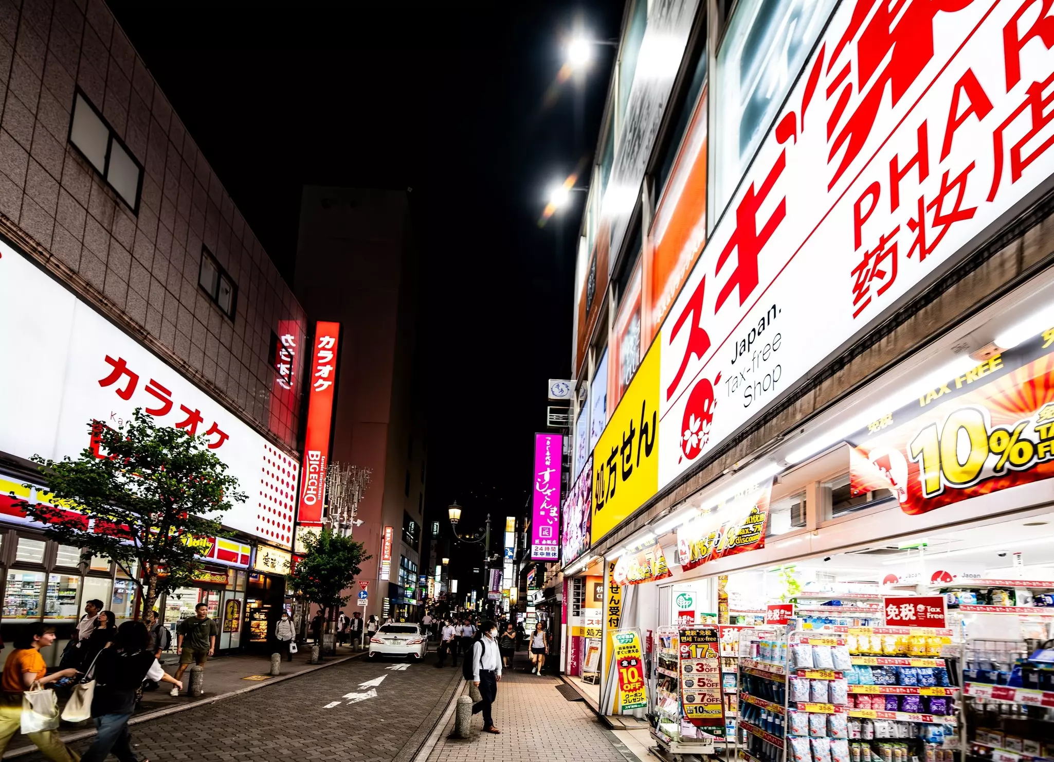 A street at night lined with shops and restaurants all lit up in neon lights