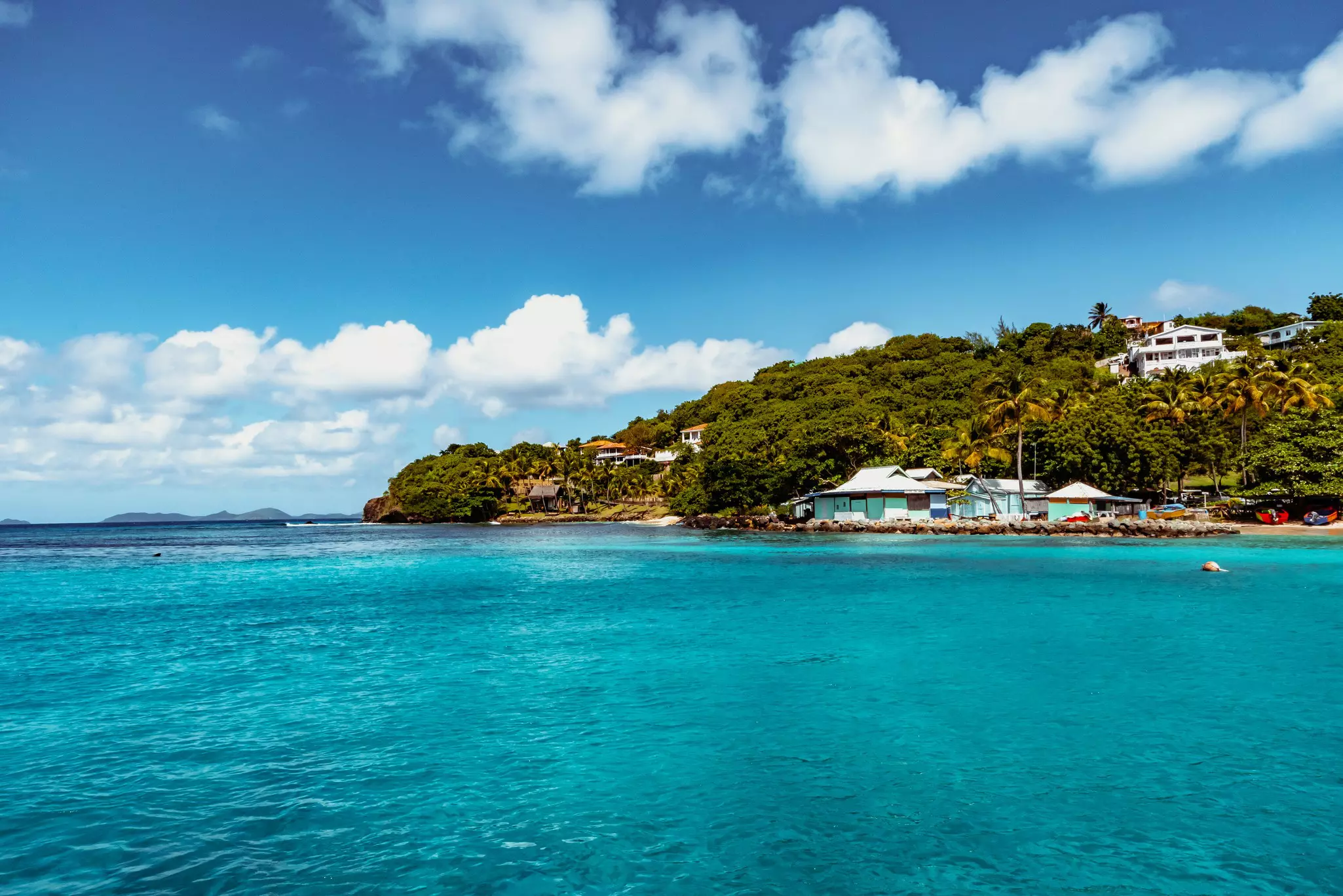 Houses on a low hillside by a turquoise bay.