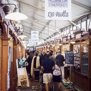 People walk past wooden stalls in a market hall in Helsinki.