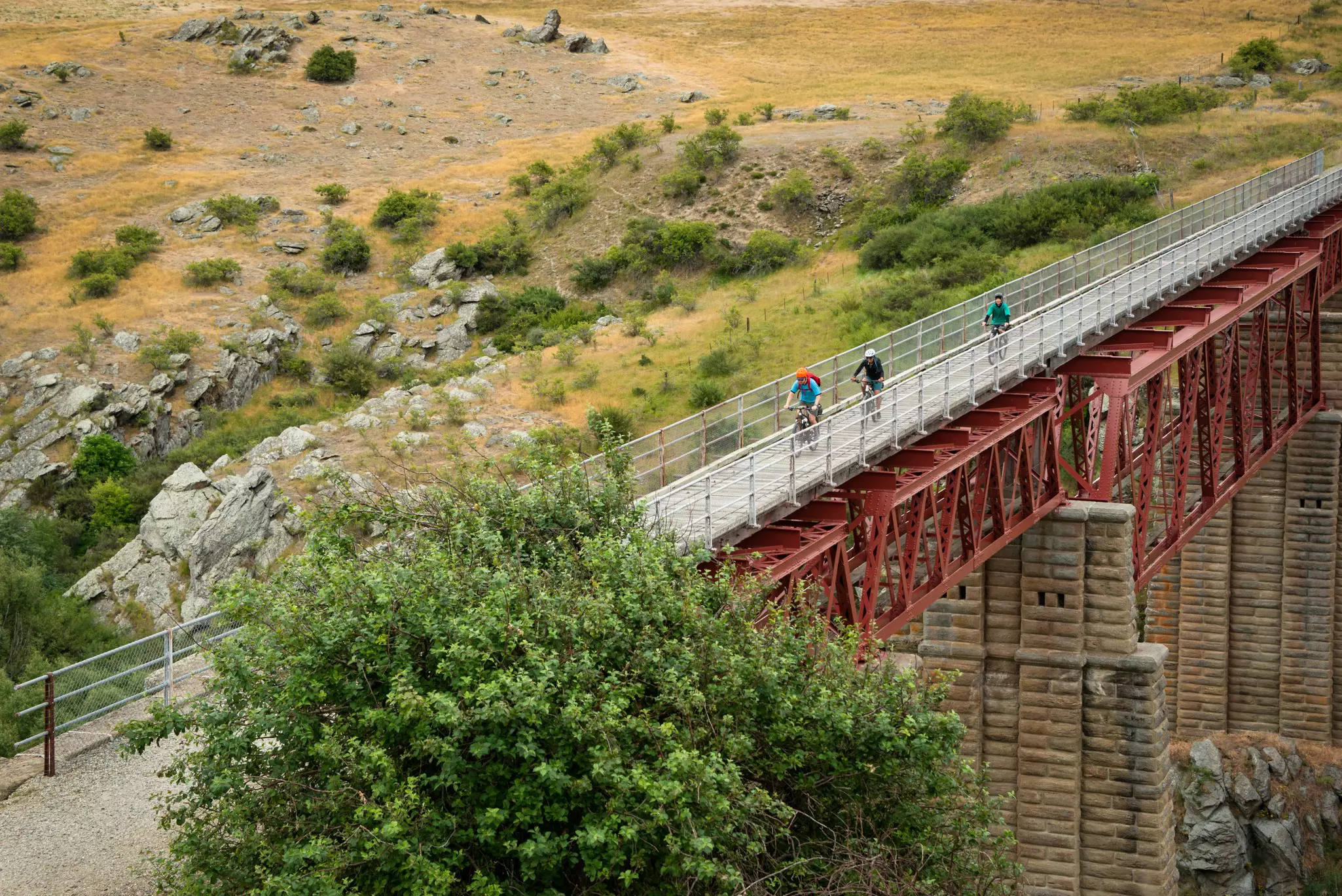 Three cyclists pedal along the trail over a former railway bridge.