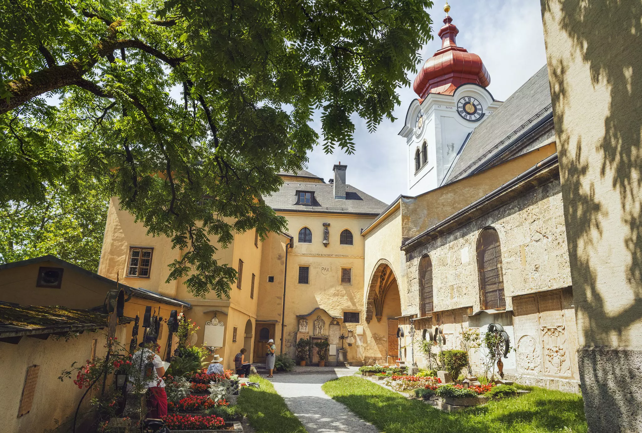 Tourists gather in the courtyard of an abbey on a summer's day