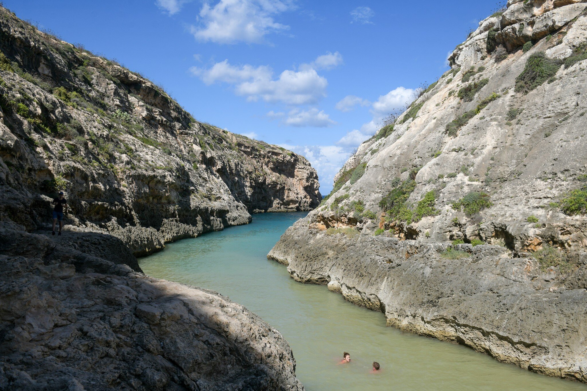 Two people in a river with large rocks on either side