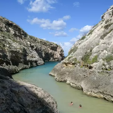 Two people in a river with large rocks on either side