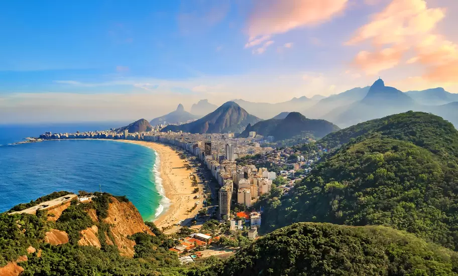 Copacabana Beach and high-rises in Rio de Janeiro, Brazil, from a forested hill, with Corcovado and Christ statue beyond