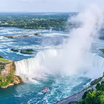Aerial of a tour boat at the base of Niagara Falls and Horseshoe Falls.