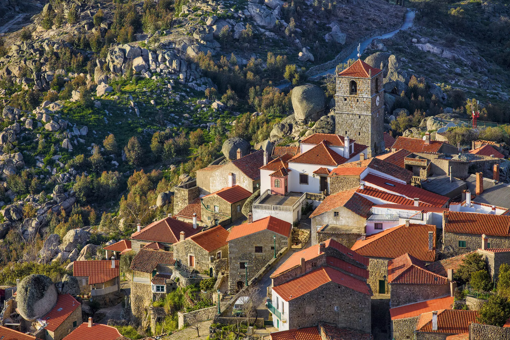 An aerial view of medieval hilltop village, with stone houses, a tower and the surrounding rocky landscape