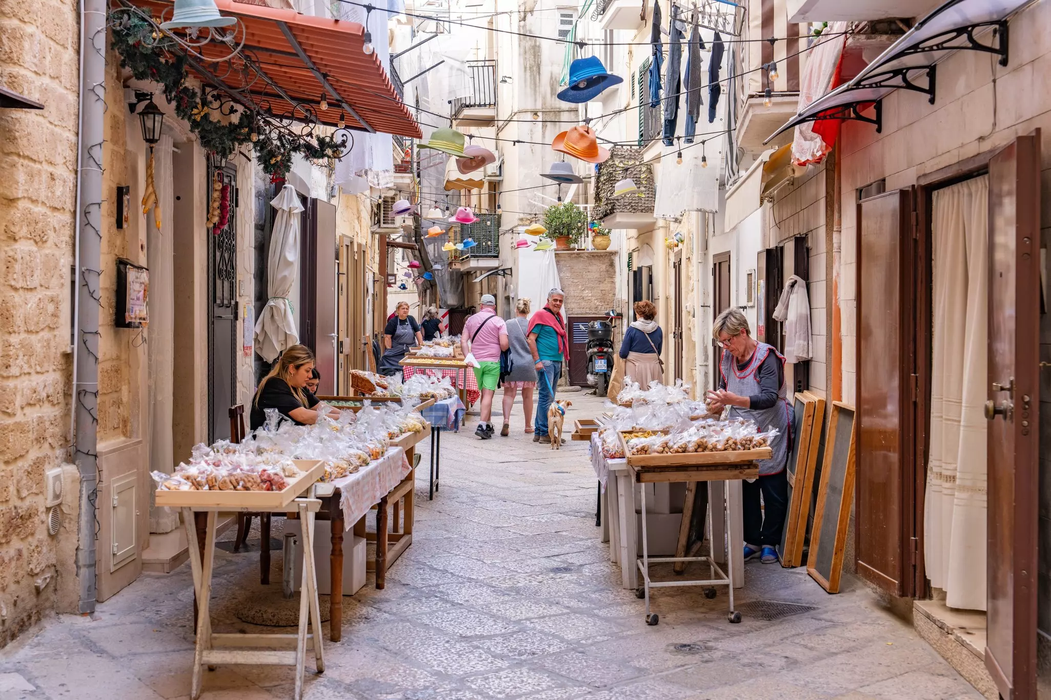 People selling handmade pasta in individual bags on a street in a historic town center in Italy.